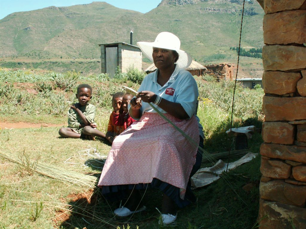 LESOTHO - een vrouw die riet aan het vlechten is in een dorp