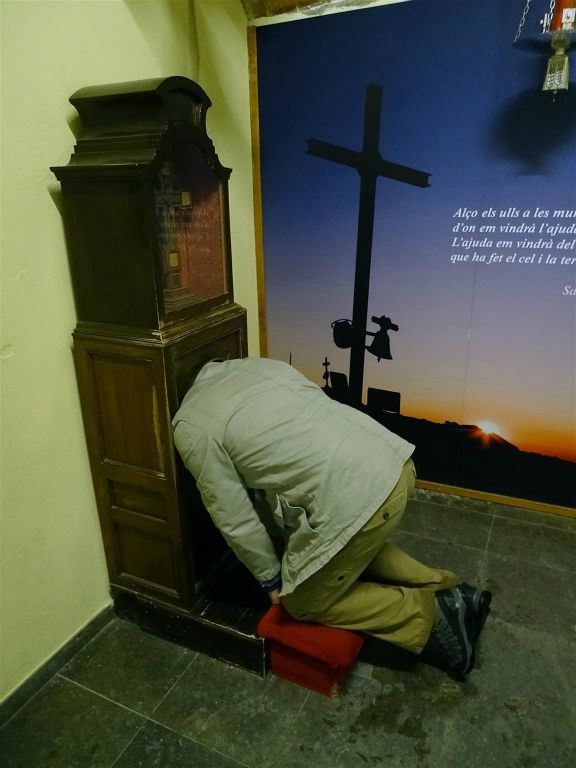 VALL DE NURIA (SPANJE) - Carlos met zijn hoofd in de  bidstoel "L'Olla de Núria" in de kerk van de maagd van Núria. Als je met je hoofd in de pot de bel luidt krijg je geen hoofdpijn meer zegt men.