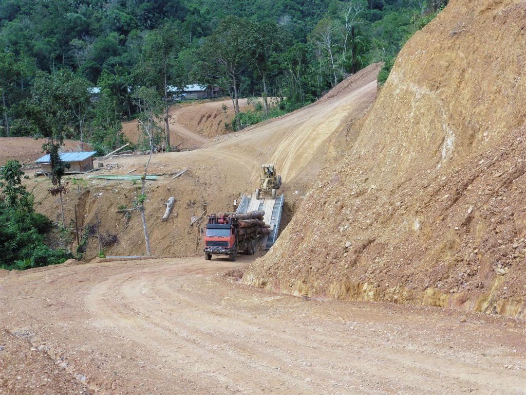 BATANG AI NATIONAL PARK - een vrachtwagen met gekapte bomen met daarachter een caterpillar om de vrachtwagen omhoog te helpen onderweg naar het tweede IBAN longhouse