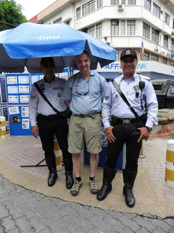 KOTA KINABALU - Carlos op de foto met twee politieagenten bij de zondagmarkt