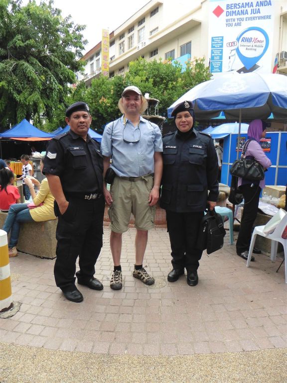KOTA KINABALU - Carlos op de foto met twee politieagenten bij de zondagmarkt