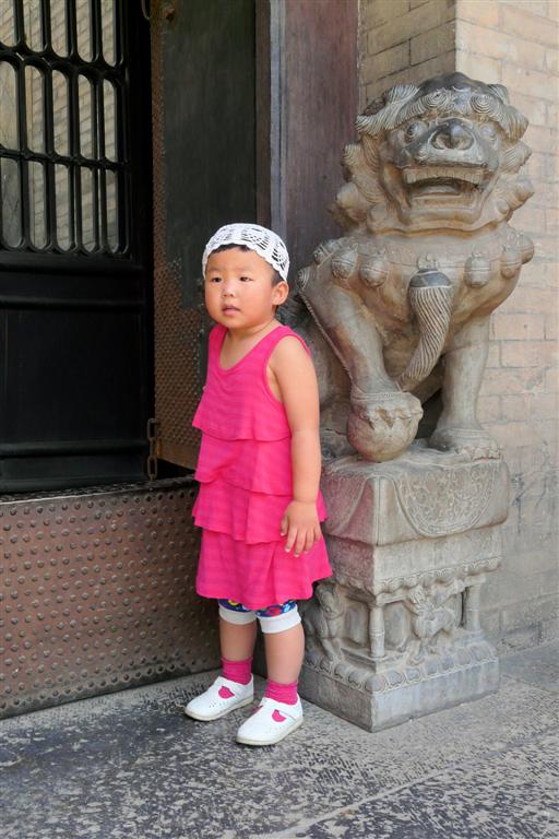 PINGYAO (Wang Family Courtyard)- meisje bij beeld van Chinese leeuw