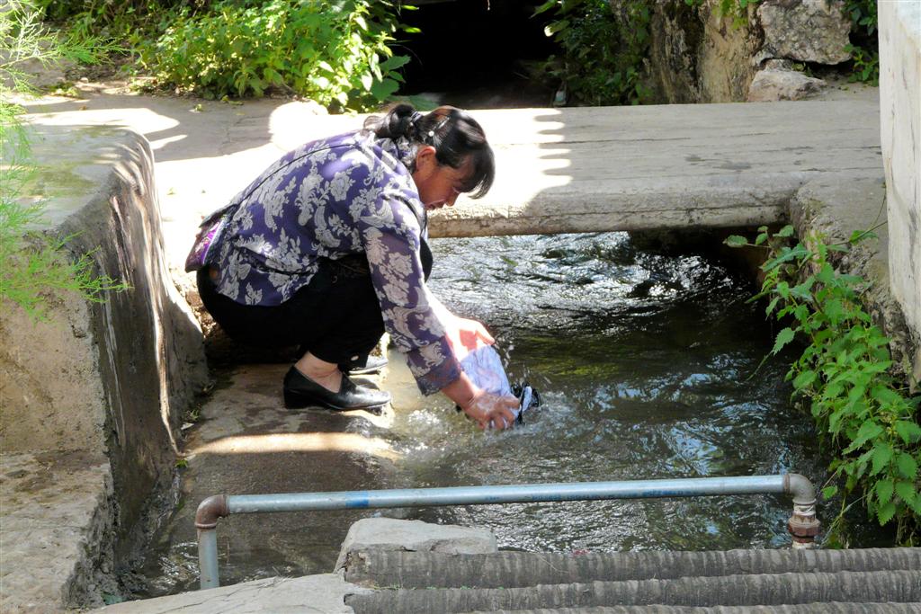 LIJIANG - een vrouw die de was doet in het dorp Baisha