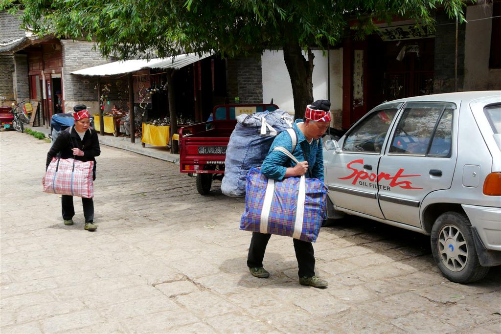LIJIANG - twee vrouwen met kledingzakken in het dorp Baisha