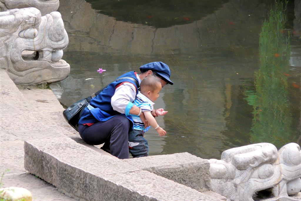 LIJIANG - een vrouw met kind aan het water in het oude centrum