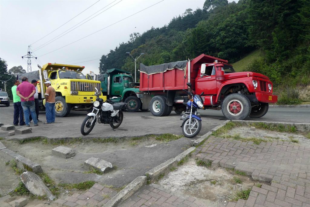 MEDELLIN - drie vrachtwagens bij een uitkijkpunt over Medellin