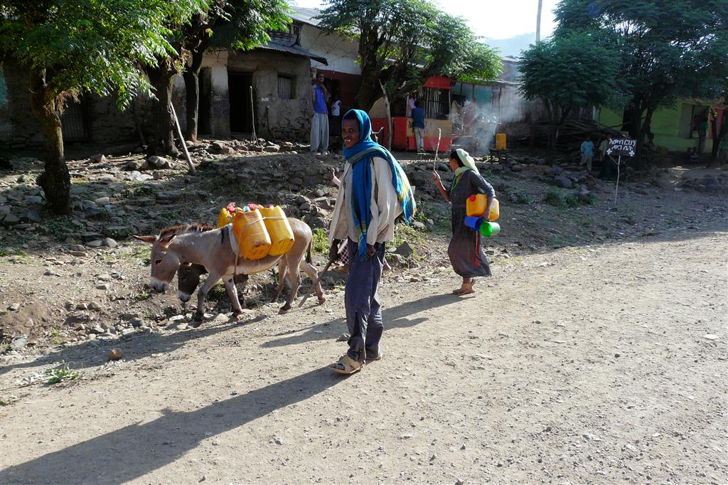 DEBARK -> AKSUM - een Ethiopische man en vrouw met hun ezels in een dorp
