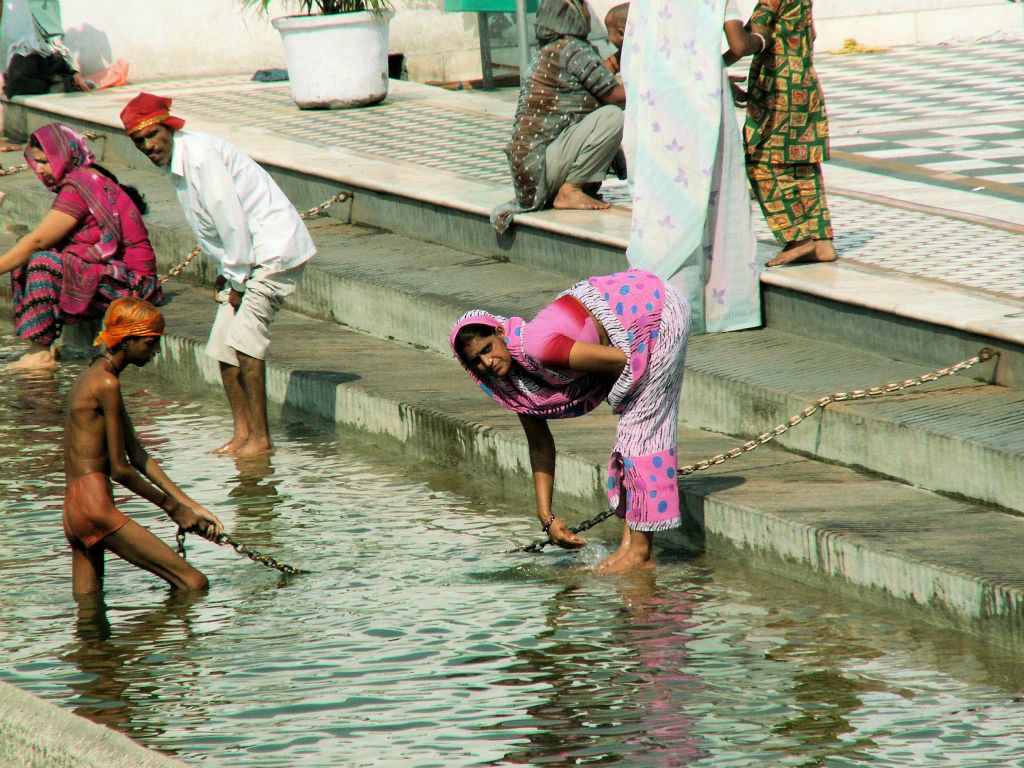 INDIA - DELHI - enkele mensen aan het baden in het bad bij de Sinh Tempel