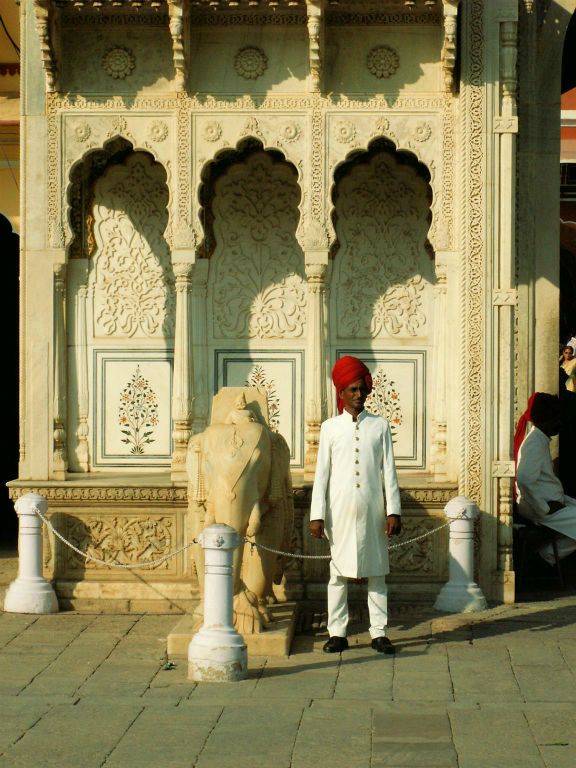 INDIA - JAIPUR - een man naast een beeld bij The City Palace
