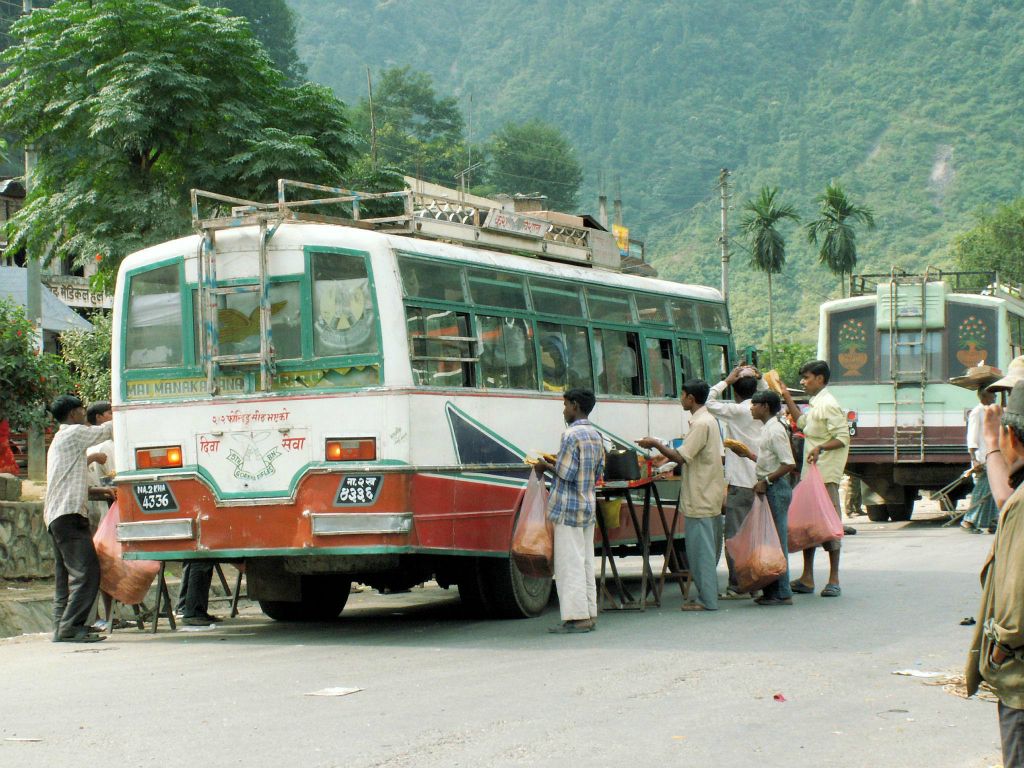 NEPAL - POKHARA -> KATHMANDU - verschillende mannen proberen hun etenswaar te slijten bij een lokale Nepalese bus