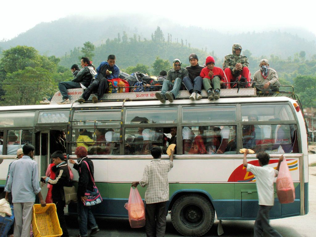NEPAL - POKHARA -> KATHMANDU - verschillende mannen proberen hun etenswaar te slijten bij een lokale Nepalese bus