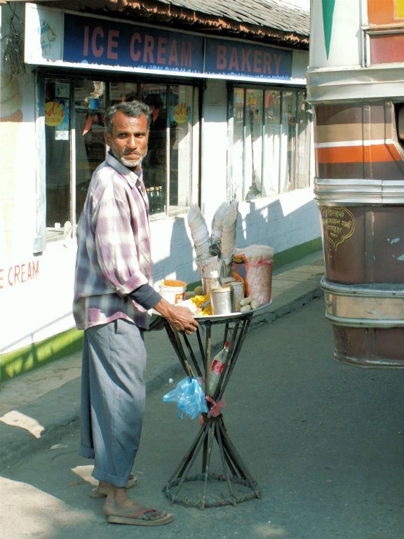 NEPAL - POKHARA -> KATHMANDU - een man die een Nepalees tussendoortje met oa mais verkoopt