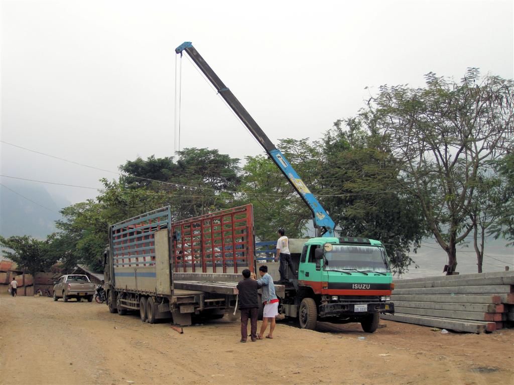 LAOS - LUANG PRABANG - betonnen balken worden op een vrachtwagen geladen
