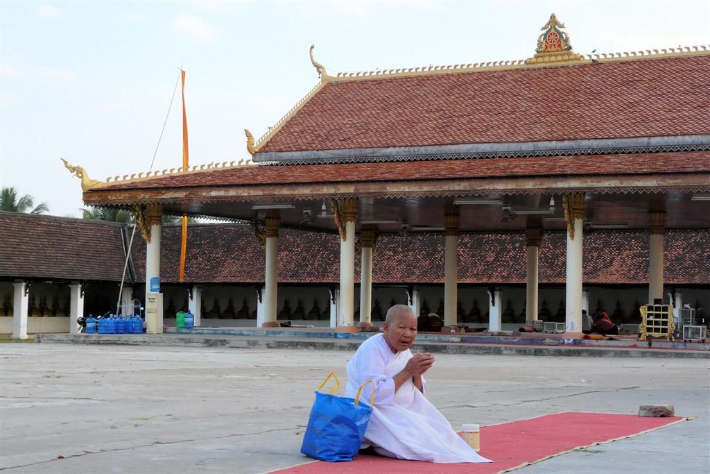 LAOS - SAVANNAKHET - monnik aan het bidden voor de That Ing Hang stupa