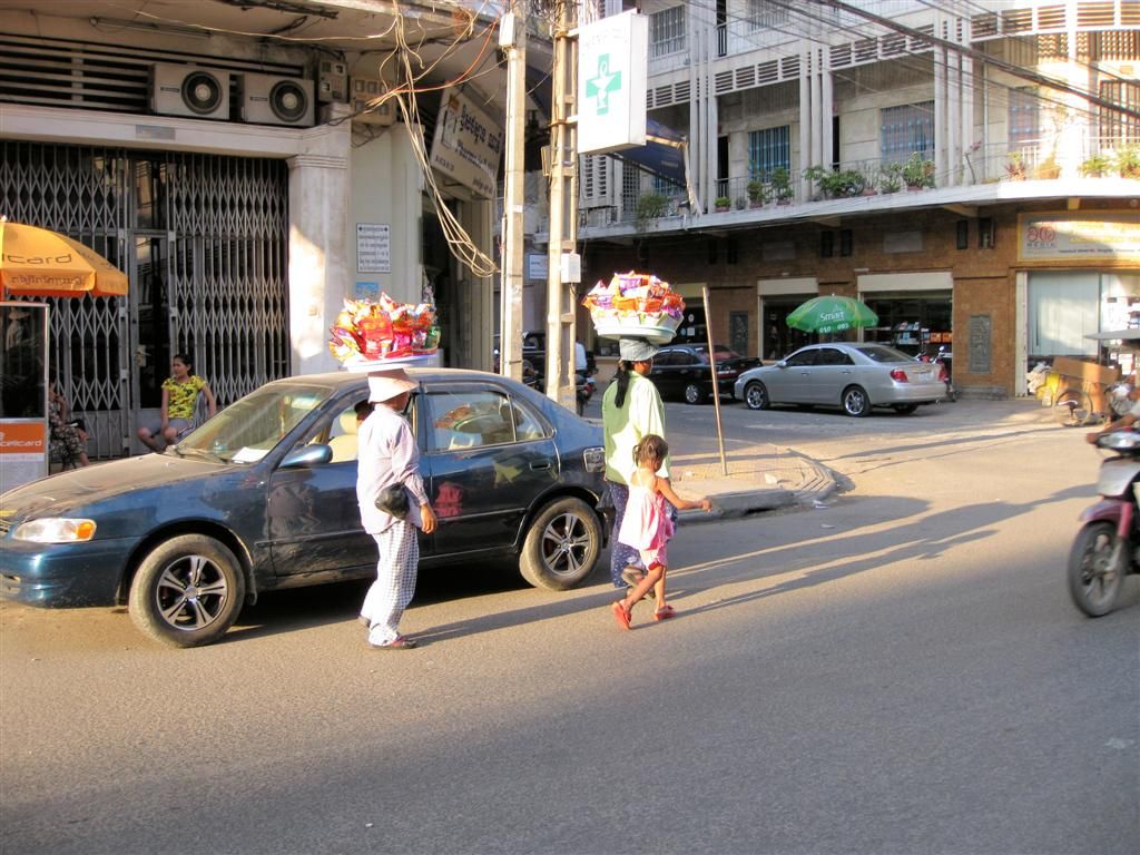 CAMBODJA - PHNOM PENH - twee vrouwen die mand met etenswaar op hun hoofd dragen