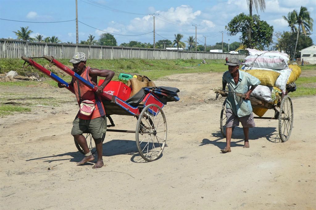 TOAMASINA - twee Malagassiërs die goederen vervoeren in een riksja
