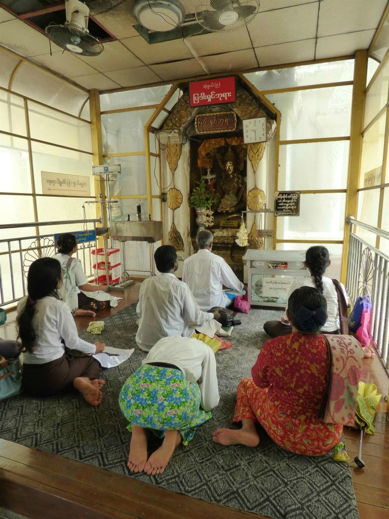 YANGON - enkele Myanmarezen aan het bidden op het complex van de Schwedagonpagode