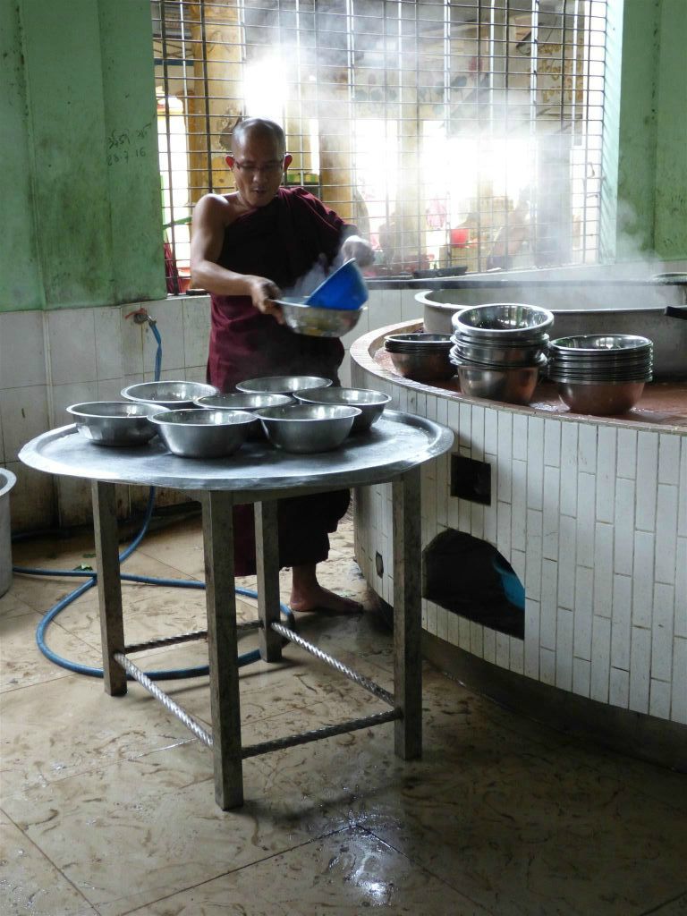 BAGO - een monnik giet eten in bakken in de keuken van het Kha Khat Wain Kyaung klooster