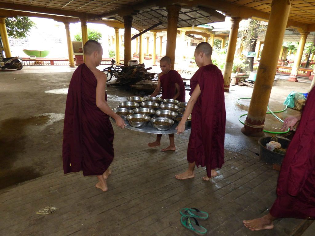 BAGO - enkele monniken dragen de bakken met eten naar de eetzaal van het Kha Khat Wain Kyaung klooster