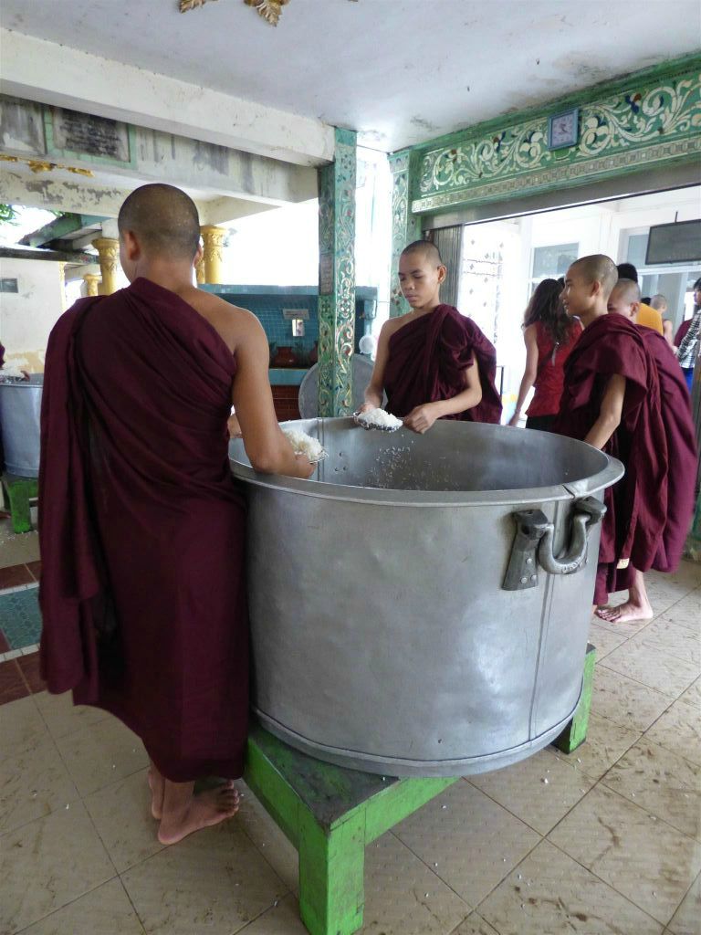 BAGO - enkele monniken serveren rijst aan de monniken bij de ingang van de eetzaal van het Kha Khat Wain Kyaung klooster
