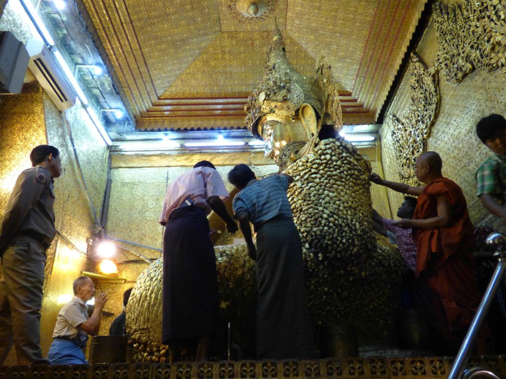MANDALAY - enkele Myanmarezen plakken goudblaadjes op de Mahamuni boeddha in de Mahamuni pagode