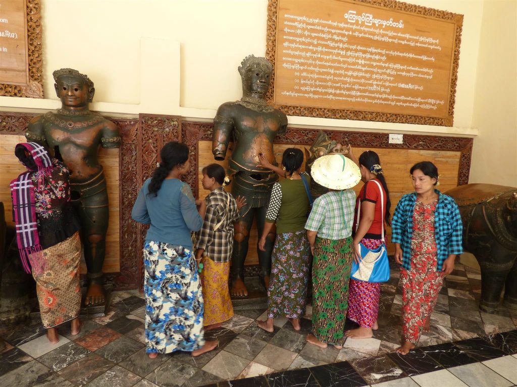 MANDALAY - enkele Myanmarezen wrijven over Khmer bronzen beelden bij het Mahamuni pagode complex