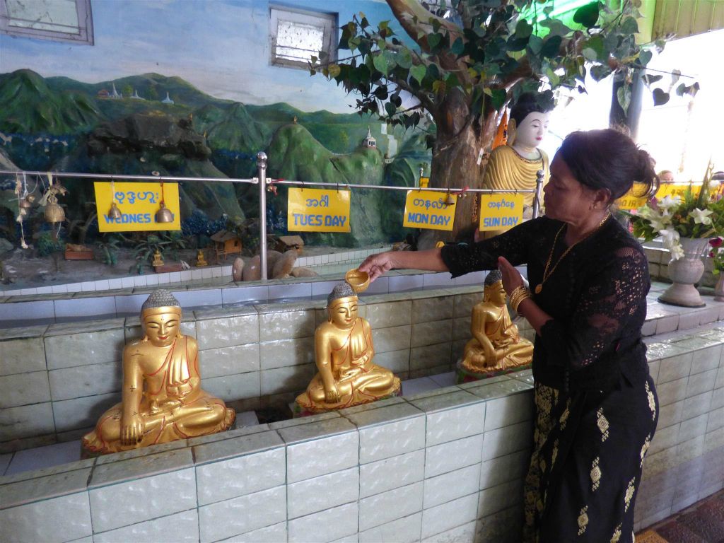 MANDALAY - een vrouw giet water over haar geboortedag boeddha bij het Mahamuni pagode complex, dit zou geluk moeten brengen