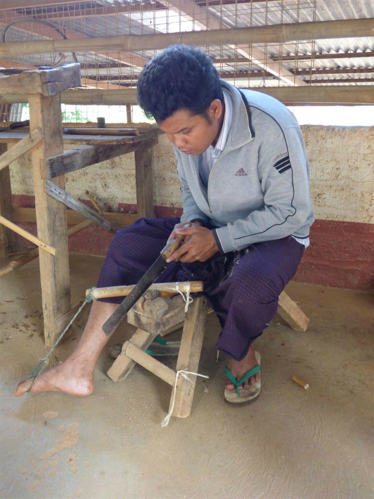 PINDAYA -> KALAW - een man in een papieren paraplu werkplaats maakt met een zaag sneden in een onderdeel voor een paraplu