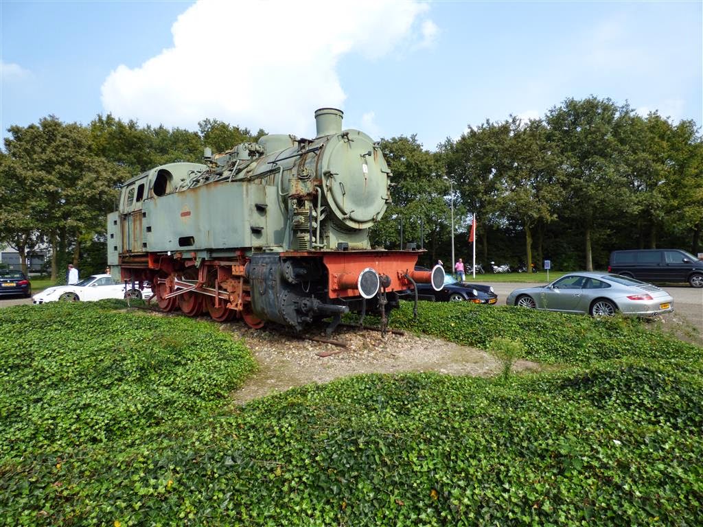 oude stoomlocomotief van het Autotron bij enkele Porsches
