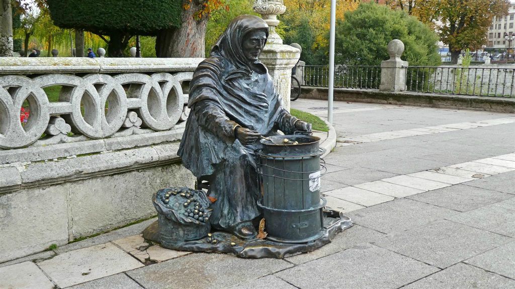 BURGOS - een bronzen beeld van een vrouw die kastanjes aan het branden is
