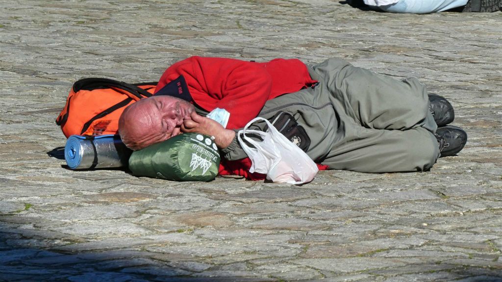 SANTIAGO DE COMPOSTELLA - een man die uitgeput is op het Obradoiro-plein
