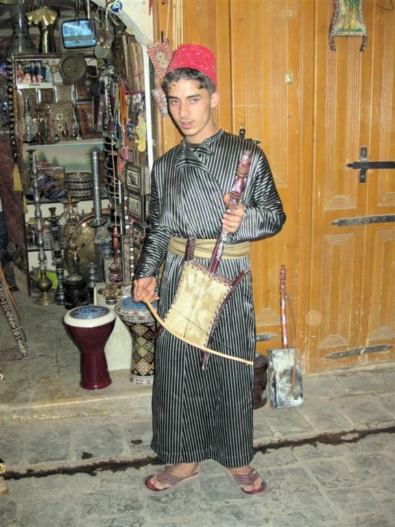 SYRIЁ - ALEPPO - jongen die een rababah snaarinstrument bespeeld