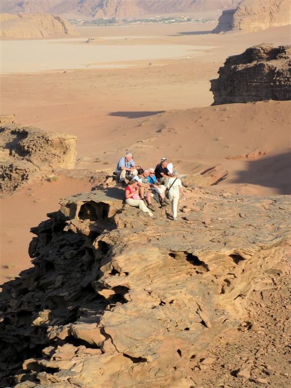 JORDANIЁ - WADI RUM - deel groepsgenoten aan het wachten voor de zonsondergang op rots in de woestijn