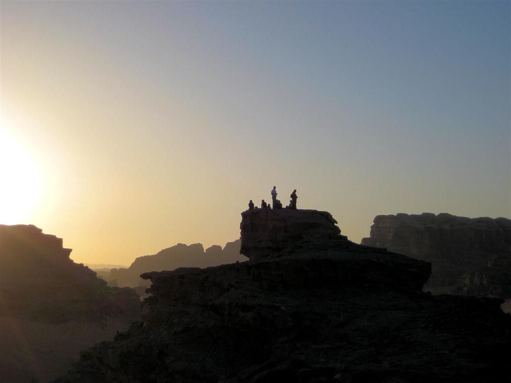JORDANIЁ - WADI RUM - Carlos en andere groepsgenoten aan het wachten voor de zonsondergang op hogere rots in de woestijn