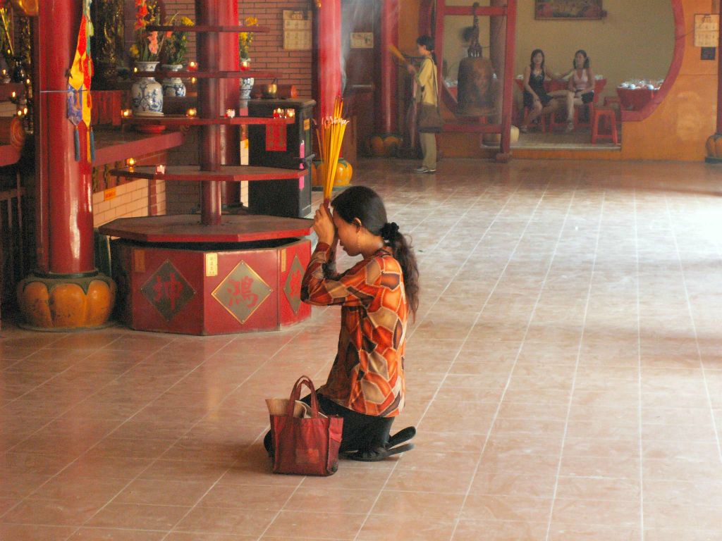 SAIGON - een vrouw aan het bidden bij een Chinese tempel