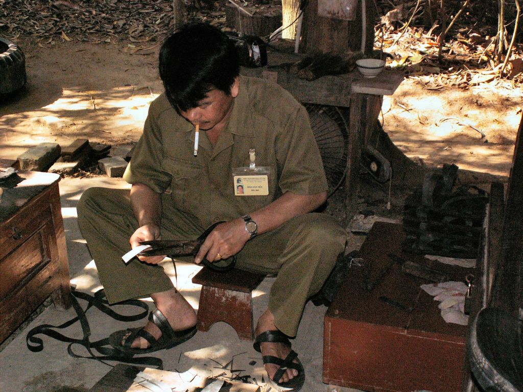 SAIGON - een man die rubberen sandalen aan het maken is